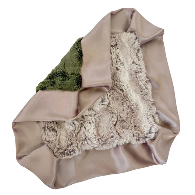 A folded throw blanket featuring a smooth taupe satin-like exterior, a plush cream sherpa-like interior, and a folded green fabric section on one side, shown against a plain white background.