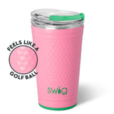 A pink textured insulated tumbler with a clear lid and green straw, shown on a white background with a circular inset highlighting the dimpled golf-ball-like texture. The word 'swig' is printed near the bottom.