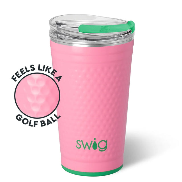 A pink textured insulated tumbler with a clear lid and green straw, shown on a white background with a circular inset highlighting the dimpled golf-ball-like texture. The word 'swig' is printed near the bottom.