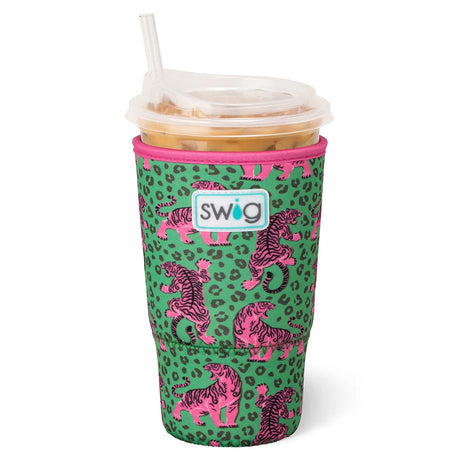 A green neoprene tumbler sleeve with a pink leopard print and pink-and-black tiger pattern, featuring a white Swig logo patch on the front. The sleeve is shown on a clear-lidded plastic cup with a straw, filled with an iced drink, against a plain white background.