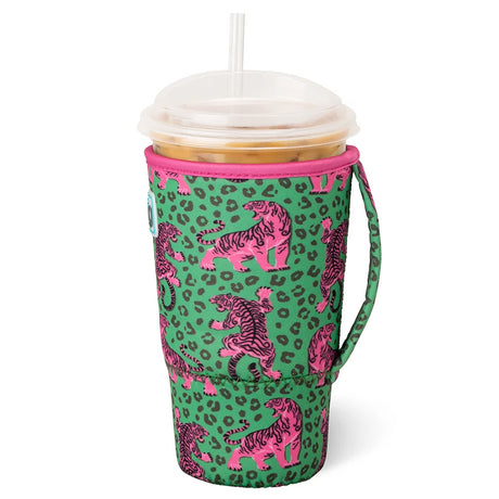 A green neoprene travel tumbler sleeve with a pink leopard print and pink tiger illustrations, shown on a clear-lidded insulated cup with a straw against a white background.