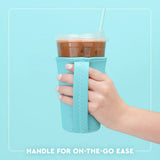 Hand holding a cup with a turquoise sleeve against a light blue background