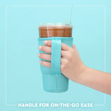 Hand holding a cup with a turquoise sleeve against a light blue background