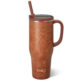 A brown insulated travel tumbler with a handle, a matching brown lid and straw, and a light beige stitched floral pattern on the front. The brand name 'swig' is printed near the bottom.
