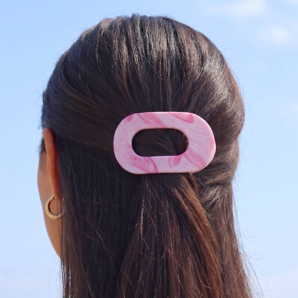 Pink marbled hair clip in a person's hair against a clear blue sky
