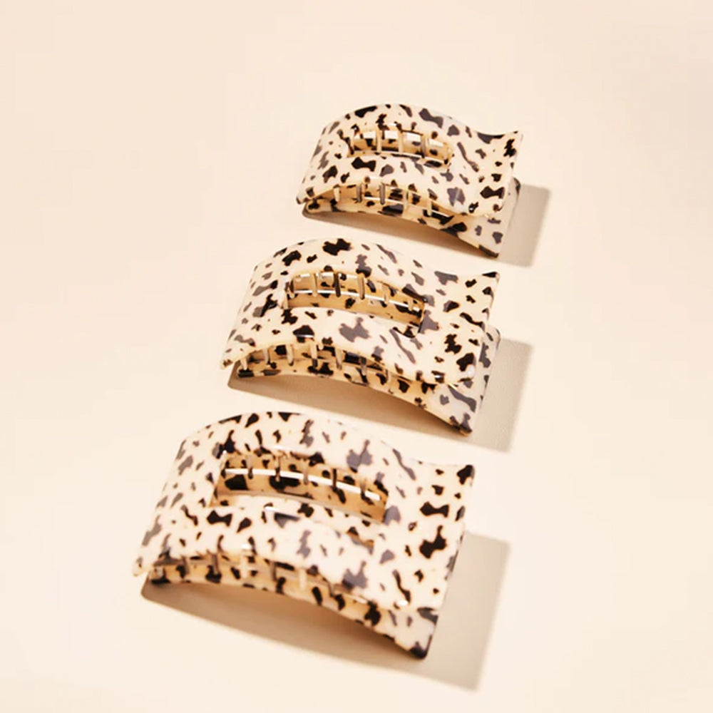 Set of three leopard print hair clips on a beige background