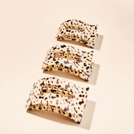 Set of three leopard print hair clips on a beige background