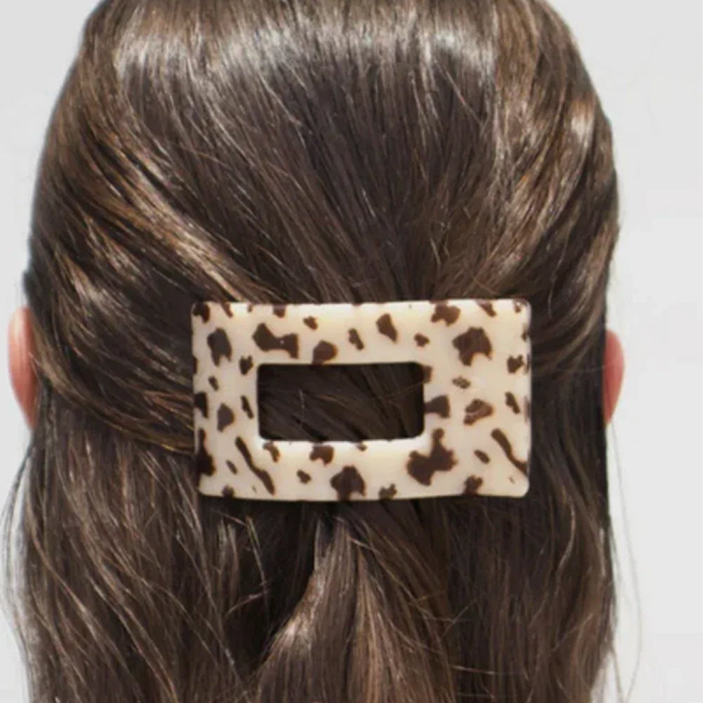 Leopard print hair clip in a person's hair against a neutral background