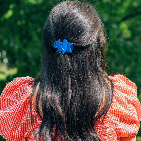 Person with long dark hair wearing a blue hair clip outdoors