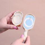 Hand holding a compact mirror with a brush on a beige background