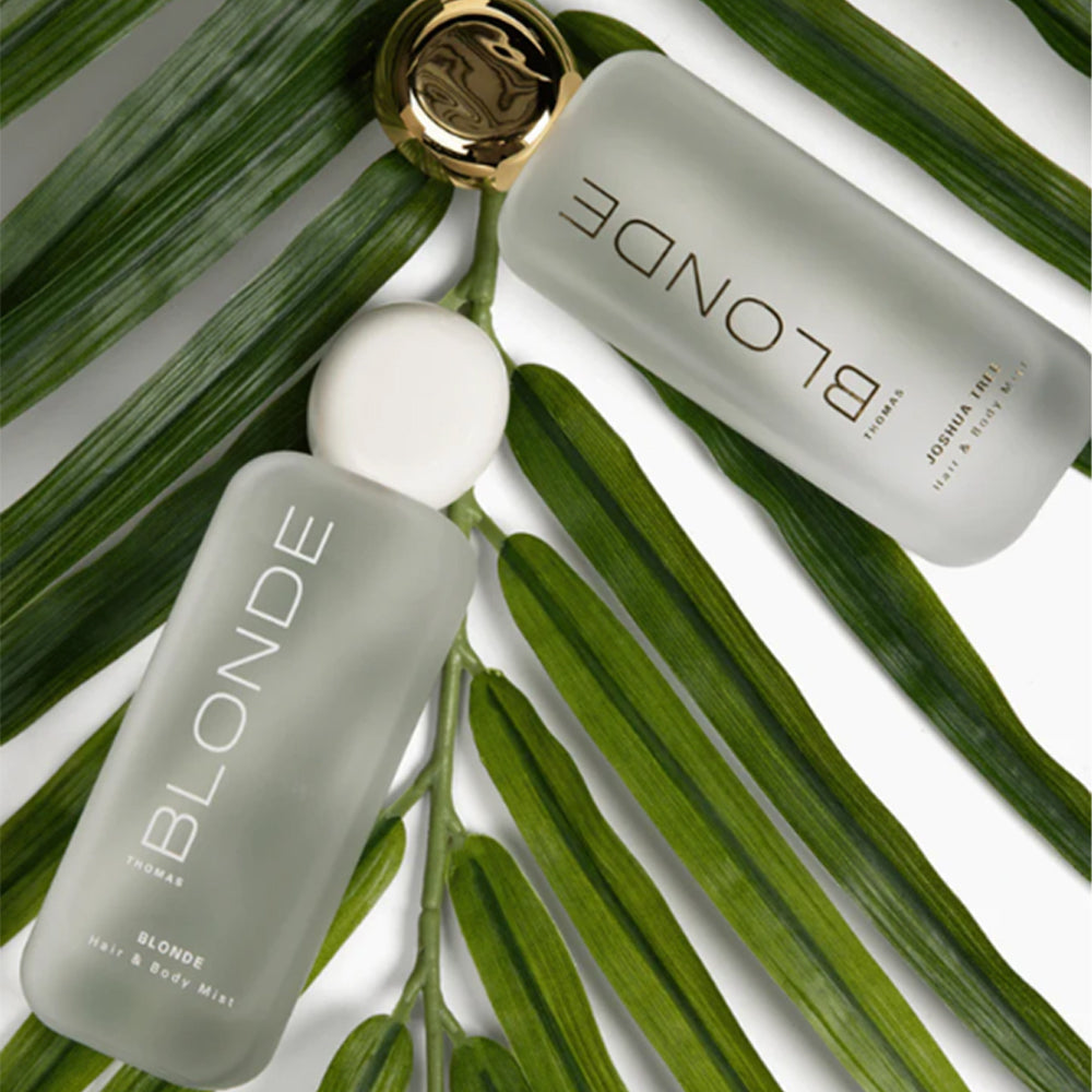 Two bottles of 'Blonde' products on green leaves with a gold cap.