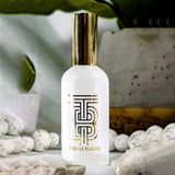 White bottle with gold cap on a natural stone surface, blurred greenery in the background