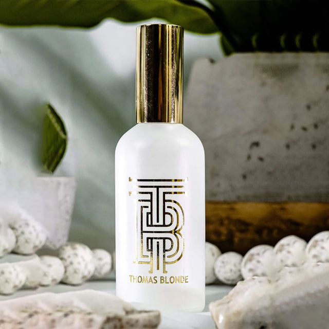 White bottle with gold cap on a natural stone surface, blurred greenery in the background