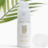 White bottle of 'Walk of Shame' dry shampoo with a palm leaf in the background