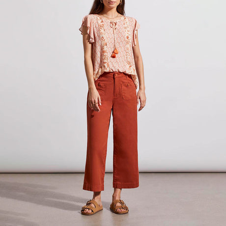 A woman wearing a pink dust blouse with tribal combo print and a casual-fit orange pantsuit.