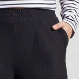 Black pants worn with a striped shirt on a plain background