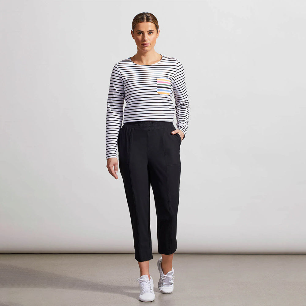 Woman wearing a striped sweater and black pants against a plain background