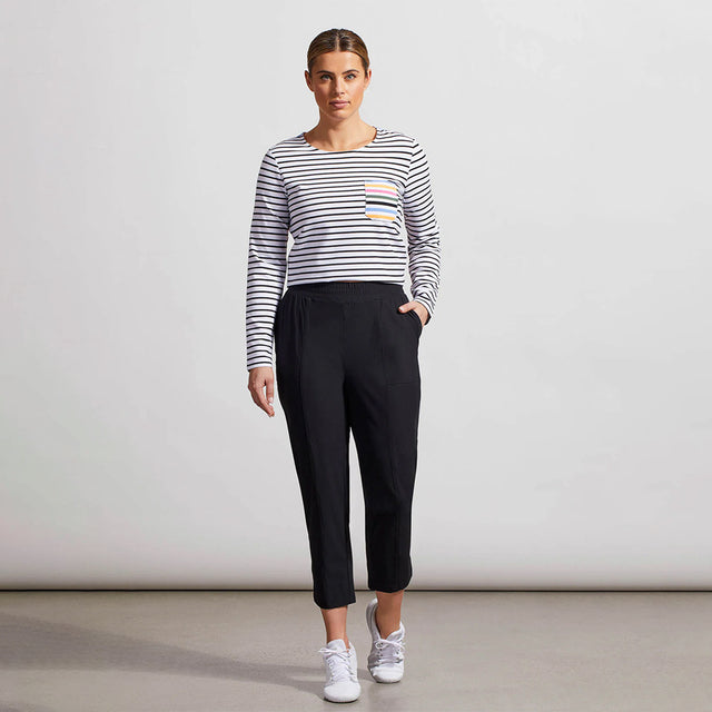 Woman wearing a striped sweater and black pants against a plain background