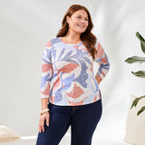 Woman wearing a patterned sweater and dark jeans against a white background