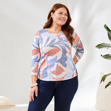 Woman wearing a patterned sweater and dark jeans against a white background