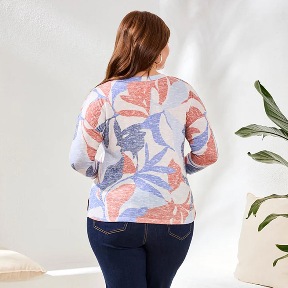 Woman wearing a colorful floral-patterned sweater in a minimal indoor setting.