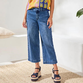 Person wearing blue jeans and a colorful top on a white background