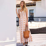Woman in a long striped dress holding a woven bag on a patio.