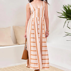 Woman wearing a striped dress in a minimal indoor setting with a plant and pillows.