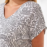 White top with black abstract pattern worn by a person