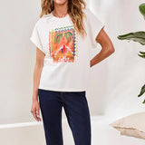 Woman wearing a white t-shirt with a colorful graphic design, standing against a plain background.