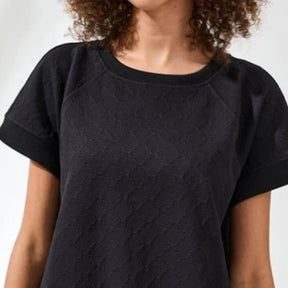 Person wearing a black textured t-shirt against a plain background