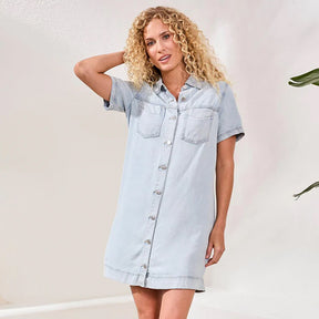 Woman wearing a light blue denim dress against a plain background