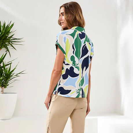 Woman wearing a colorful patterned shirt in a minimal indoor setting