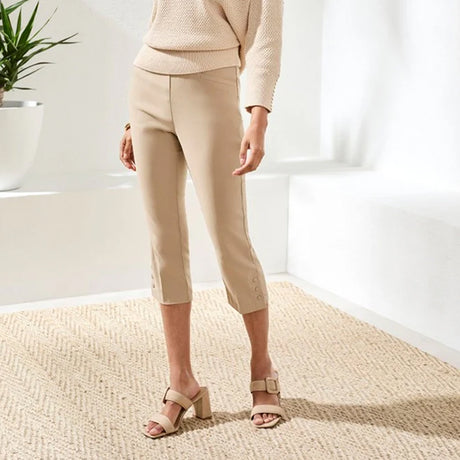 Person wearing beige pants and shoes in a minimalistic room with a plant.