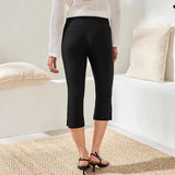 Person wearing black capri pants in a minimalistic room with white walls and a white sofa.