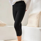 Person wearing black capri pants with a neutral background