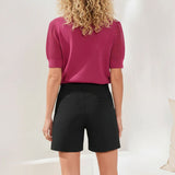 Person wearing a pink top and black shorts on a plain background
