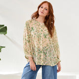 Woman wearing a floral blouse and jeans against a white background