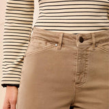 Close-up of a person wearing tan straight-leg denim jeans with a black and cream striped long-sleeve top, showing the waistband, belt loops, button, and front pocket details.
