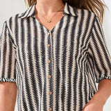 Person wearing a black and white patterned shirt with a neutral background