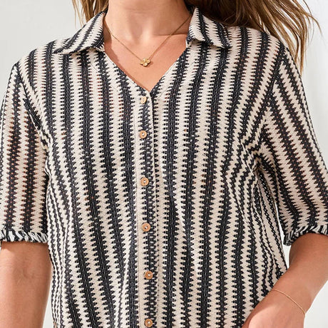 Person wearing a black and white patterned shirt with a neutral background