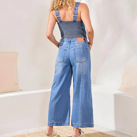 Person wearing blue denim overalls in a minimal indoor setting