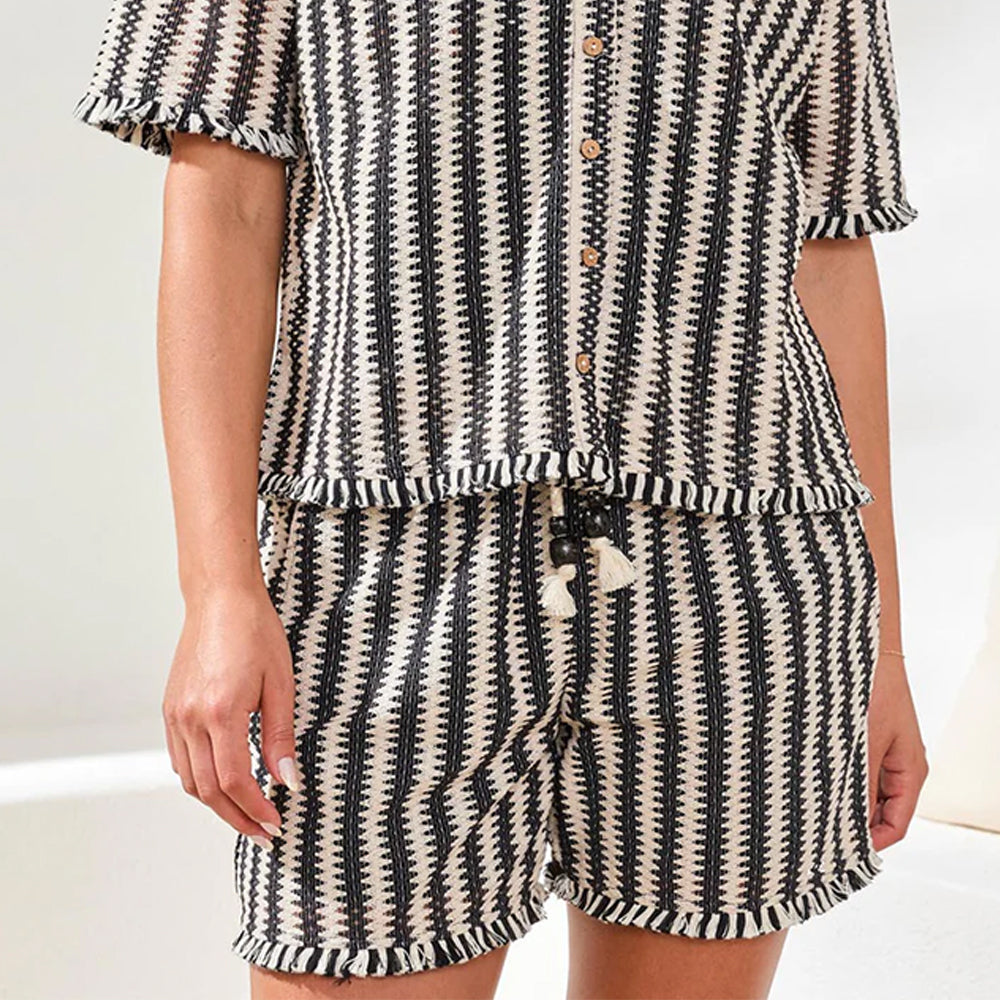 Person wearing a black and white patterned pajama set on a light background