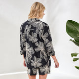 Woman wearing a black floral patterned outfit against a white background