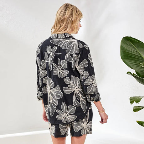 Woman wearing a black floral patterned outfit against a white background