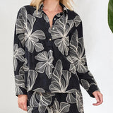 Black shirt with white floral pattern worn by a person on a white background