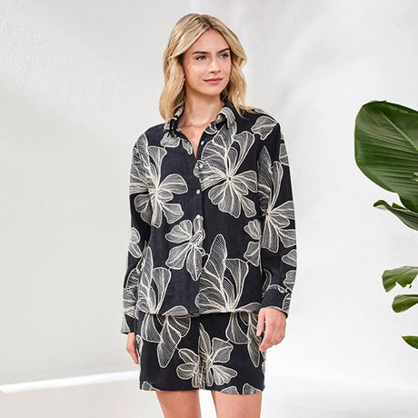 Woman wearing a black dress with white floral pattern against a white background