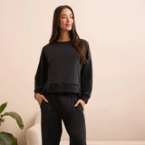 Woman wearing a black outfit against a beige wall