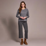 Woman wearing a gray sweater and pants with brown boots on a beige background