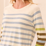 A close-up of a person wearing a long-sleeve knit top with horizontal stripes in cream, light blue, olive green, and brown.